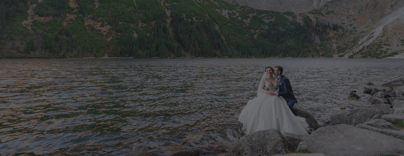 A couple sitting by a lake with mountains in the background